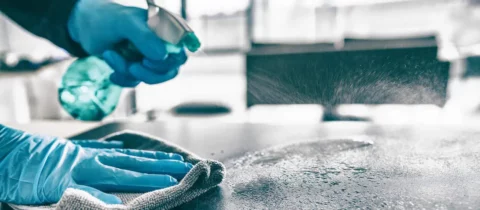 Professional cleaner spraying and wiping down a surface with disinfectant during move-out cleaning