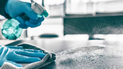 Professional cleaner spraying and wiping down a surface with disinfectant during move-out cleaning