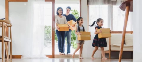 Happy family carrying boxes into their new home on moving day