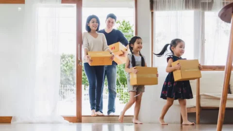 Happy family carrying boxes into their new home on moving day