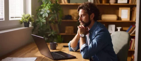 Man working on a laptop at home comparing reviews of local moving companies