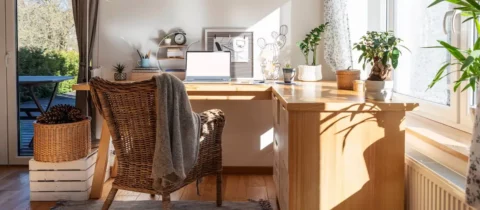 Bright home office with large wooden desk and laptop near window