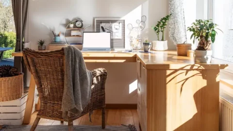 Bright home office with large wooden desk and laptop near window