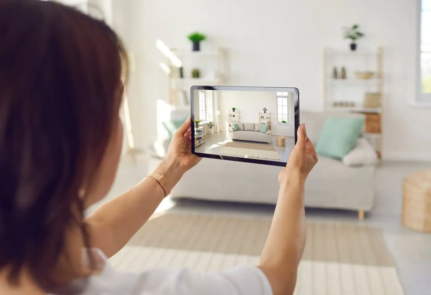 Woman using a tablet to photograph a staged living room before moving out.