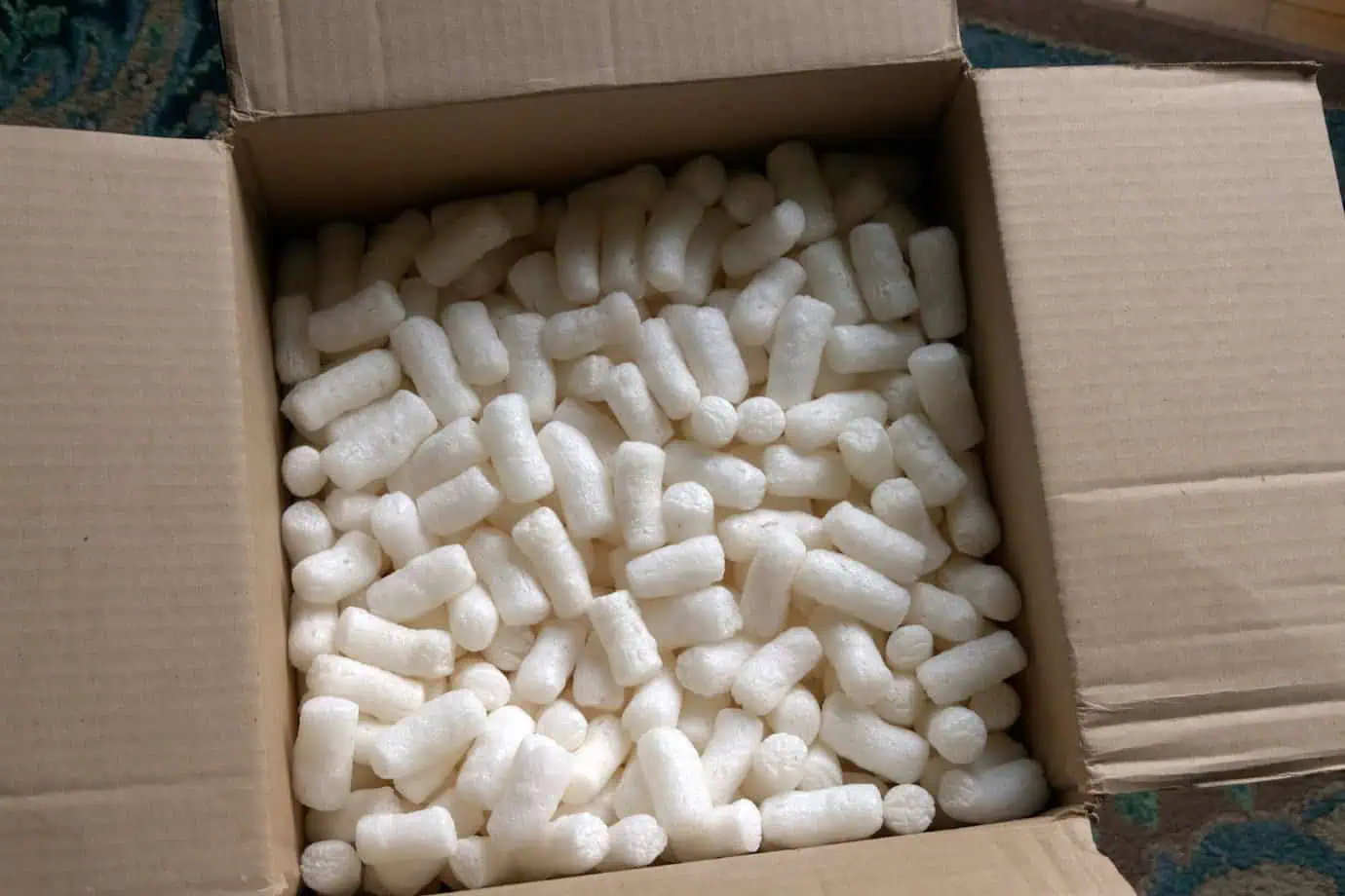 Open cardboard box filled with white packing peanuts for cushioning fragile items