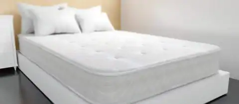 Clean mattress on a bed frame in a bedroom, ready for donation